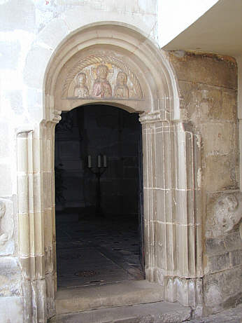 Romanisches Stufenportal mit Tympanon, links und rechts mit Löwenreliefs an der Wand.