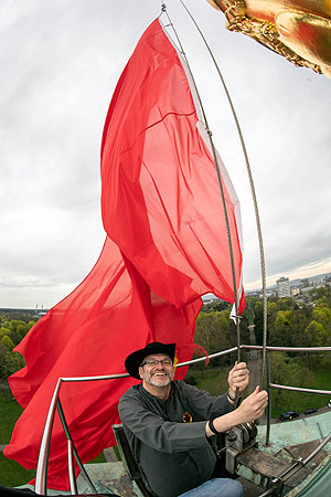 Kurator Oliver Sänger hisst die rote Fahne, i.R. der Sonderausstellung „Revolution! Für Anfänger*innen“ © Badisches Landesmuseum, Foto: Uli Deck