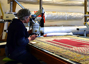 rem-Textilrestauratorin Sylvia Mitschke untersucht einen Teppich mithilfe eines Auflichtmikroskops