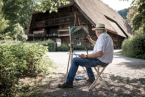 Schwarzwaldmaler Wolfram Paul vor dem Gebäude des Vogtsbauernhofs